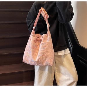 Macro detail of pink textured canvas bag with colorful wavy embroidery and adjustable strap