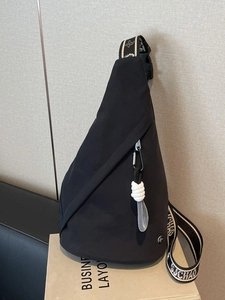 Minimalist black triangular nylon sling bag with metal carabiner and striped strap