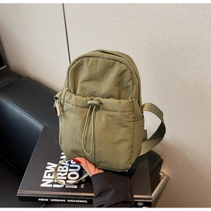 Detail of olive green nylon bag with drawstring pocket on a book, casual urban style