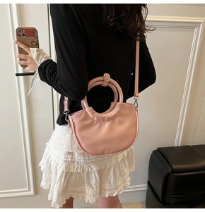 Rear view of a model carrying the pink half-moon crossbody bag with round handles