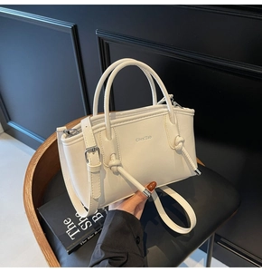 Dettaglio della borsa tote in pelle crema con manici annodati e logo del marchio
