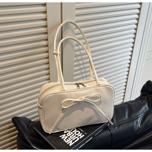 Detailed view of the large bow decoration and dual straps on the off-white crossbody bag