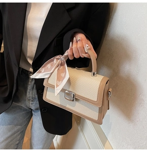 Détail du sac à main contrasté avec fermoir rotatif argenté et foulard sur la poignée