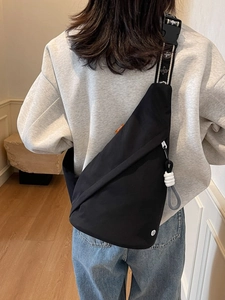 Minimalist black nylon sling bag with geometric pattern strap and orange detail tag