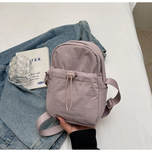 Close-up of lavender nylon crossbody bag featuring drawstring pocket and adjustable strap