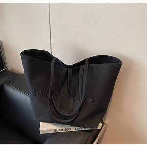 Detail of black canvas tote bag showing high-quality fabric texture and 3D embossed lettering