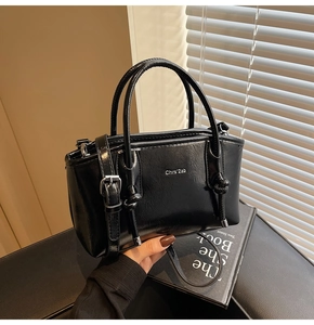 Dettaglio borsa shopper nera in pelle con fibbia argento e nodo su uno sfondo neutro