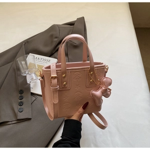 Detailansicht der pinkfarbenen PU-Eimertasche mit Prägung, Anhänger und Goldbeschlägen