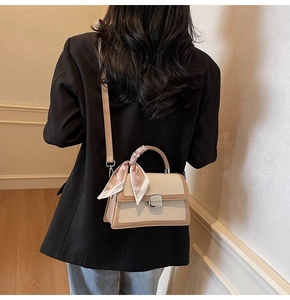 Détail du sac à main tissé beige avec bordure en cuir marron et anse en foulard de soie