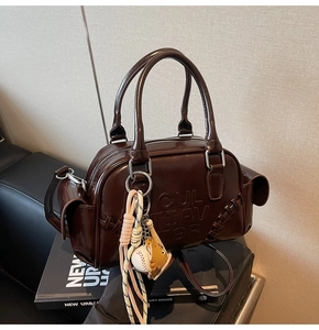 Detail of dark brown leather Boston bag featuring embossed letters and baseball charms