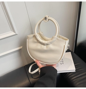 Detailed shot of cream half-moon bucket bag with oversized ring handle and shoulder strap