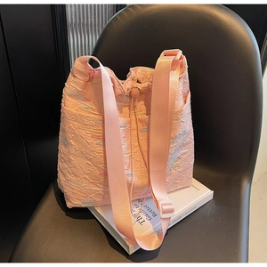 Close-up of pink quilted bucket bag with colorful wavy embroidery on a modern chair