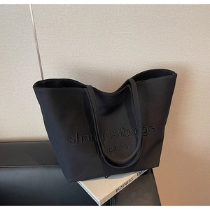 Detail of black canvas tote bag showing high-quality embroidery and durable shoulder straps