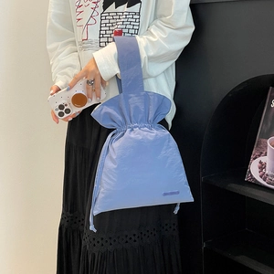 Close-up of a light purple drawstring nylon handbag with a wide handle held by a model