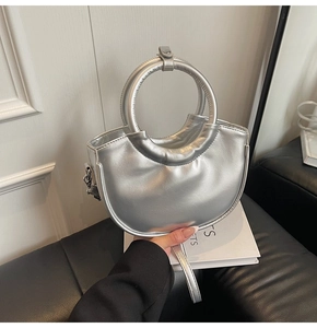 Close-up of metallic silver half-moon handbag featuring a large circular ring handle