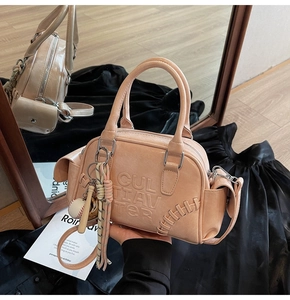 Detail of apricot Boston bag with CULTIAVTER embossed logo and baseball charm