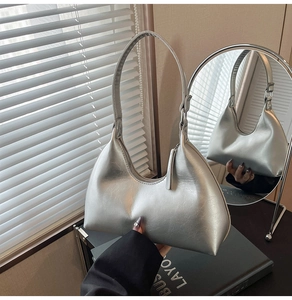Detail of silver metallic crescent bag showing its textured surface and sleek zipper closure