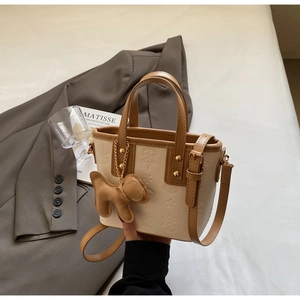 Details der Vintage-Tasche in Beige mit Sternprägung und süßem Hundeanhänger