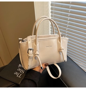 Dettaglio borsa tote in pelle PU color crema con nappa annodata e logo del marchio