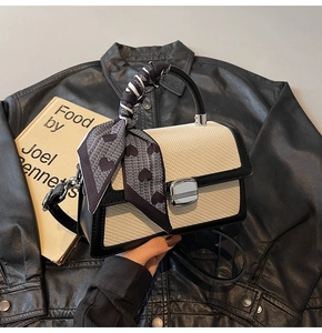 Détail du sac bandoulière bicolore avec foulard en soie à cœurs et fermoir argenté