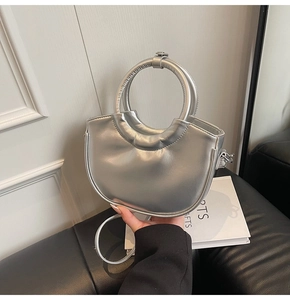 Detail of silver crescent handbag with metallic finish and oversized circular handle