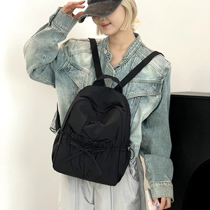 Detail of classic black nylon backpack featuring a decorative bow and adjustable straps