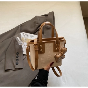 Detail einer eleganten Tasche mit Sternprägung, braunem Griff und Bärchen-Anhänger