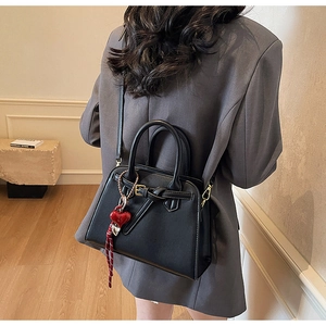 Moderna borsa a tracolla trapezoidale nera vista da dietro su modella con blazer grigio