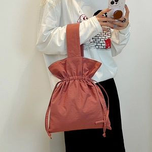 Detail of minimalist brick red nylon drawstring bag with textured fabric and wide handle
