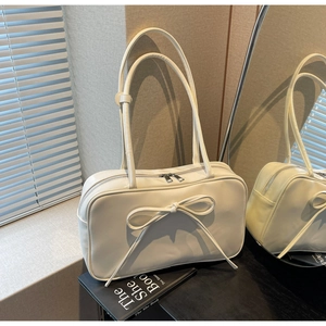 Detail of cream bow tote bag showing smooth leather texture and elegant silver zippers