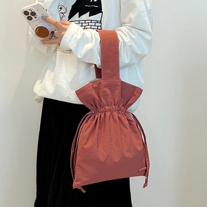 Detail of drawstring bucket bag in brick red nylon with pleated ruffled top and wide handle