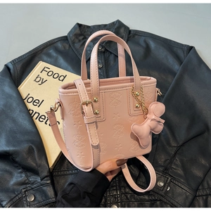 Detail der rosa geprägten Beuteltasche mit goldener Hardware und süßem Bärenanhänger