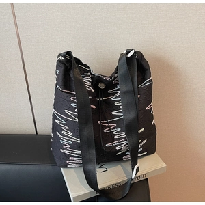 Detail of black quilted canvas tote with colorful wave embroidery and drawstring closure