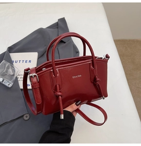 Dettaglio della borsa tote in pelle bordeaux lucida con logo argento e tracolla
