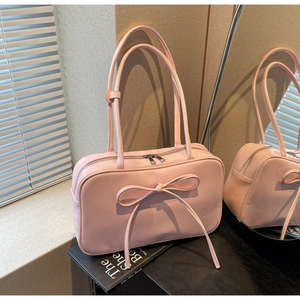 Detail of light pink shoulder bag with large bow decoration and silver metal zipper closure