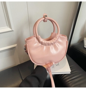 Detail of pink leather handbag showing unique ring handle and elegant pleat texture