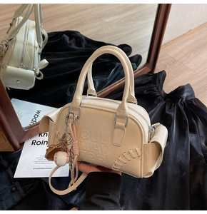 Detail of cream Boston bag featuring baseball stitching, 3D embossing and glove charm