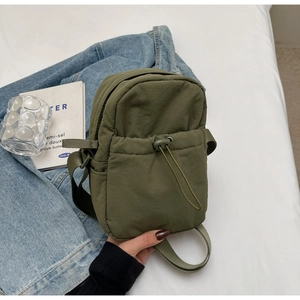Detailed view of an olive green drawstring crossbody bag on a clean minimalist background