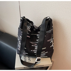 Detail of black wave embroidered canvas tote bag with adjustable nylon strap and textures