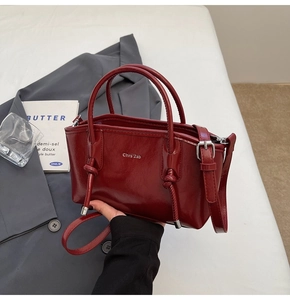 Dettaglio della borsa tote in vernice rosso scuro con nodi intrecciati e logo