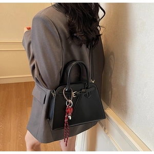 Dettaglio di una borsa a mano trapezoidale in ecopelle nera con ciondolo a cuore rosso