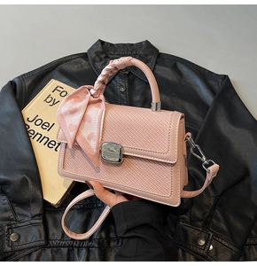 Détail d'un sac à main rose tressé avec fermoir rotatif argenté et foulard décoratif