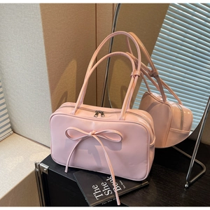 Detailed view of pink bow tote bag with metallic zipper and glossy finish on shelf