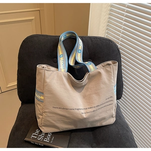 Détail du sac fourre-tout kaki avec bandoulière fleurie posé sur une chaise
