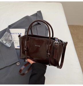 Dettaglio della borsa tote in pelle lucida marrone scuro con manico a nodo e tracolla