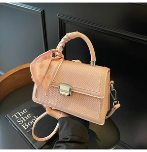 Détail du sac à main rose tressé avec boucle métallique et foulard en soie décoratif