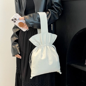 Detailed view of cream nylon drawstring handbag with wide handle and pleated texture
