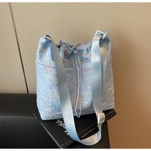 Detail of light blue pleated canvas bag featuring colorful wave stitching and nylon strap