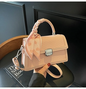 Détail du sac bandoulière rose avec texture tissée et foulard en soie à motif cœur