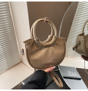 Close-up of beige crescent bag with round handles and glossy leather texture
